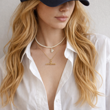 A polished gold chain necklace featuring a T-bar pendant drop at the center. The design highlights a modern, structured silhouette with timeless charm and a subtle statement finish