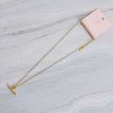 A polished gold chain necklace featuring a T-bar pendant drop at the center. The design highlights a modern, structured silhouette with timeless charm and a subtle statement finish