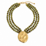 Necklace with green beads and a gold pendant on a white background