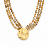 Three-strand beaded necklace with a gold pendant on a white background