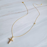 An elegant gold-tone necklace featuring a cross pendant made of luminous pearls with a sparkling crystal at the center. The pendant hangs from a 24-inch chain with a 2-inch extender, creating a timeless and graceful look perfect for layering or wearing solo.