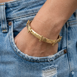 Gold bracelet on a wrist with blue jeans