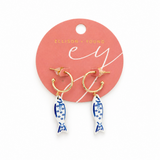 Gold hoop earrings with fish designs on a pink Ellison & Young card.