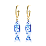 Gold hoop earrings with blue fish-shaped charms on a white background