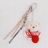 Plush bear bag charm dressed in a cozy Nordic-style sweater with knit patterns and warm tones. The bear features a soft, fluffy texture, dangling legs, and a playful expression, making it a charming accessory for bags, backpacks, or keychains.