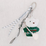 Plush bear bag charm dressed in a cozy Nordic-style sweater with knit patterns and warm tones. The bear features a soft, fluffy texture, dangling legs, and a playful expression, making it a charming accessory for bags, backpacks, or keychains.