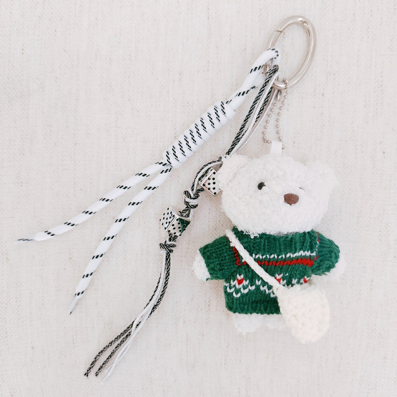 Plush bear bag charm dressed in a cozy Nordic-style sweater with knit patterns and warm tones. The bear features a soft, fluffy texture, dangling legs, and a playful expression, making it a charming accessory for bags, backpacks, or keychains.