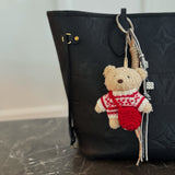 Plush bear bag charm dressed in a cozy Nordic-style sweater with knit patterns and warm tones. The bear features a soft, fluffy texture, dangling legs, and a playful expression, making it a charming accessory for bags, backpacks, or keychains.
