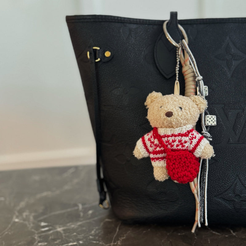 Plush bear bag charm dressed in a cozy Nordic-style sweater with knit patterns and warm tones. The bear features a soft, fluffy texture, dangling legs, and a playful expression, making it a charming accessory for bags, backpacks, or keychains.