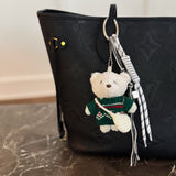 Plush bear bag charm dressed in a cozy Nordic-style sweater with knit patterns and warm tones. The bear features a soft, fluffy texture, dangling legs, and a playful expression, making it a charming accessory for bags, backpacks, or keychains.