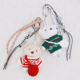 Plush bear bag charm dressed in a cozy Nordic-style sweater with knit patterns and warm tones. The bear features a soft, fluffy texture, making it a charming accessory for bags, backpacks, or keychains.