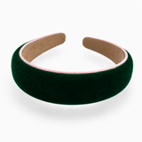 A wide, padded velvet headband in deep forest green with a light pink inner lining and tan backing, shown on a clean white background.