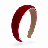 A curved velvet headband in deep red with a light pink inner lining and a beige fabric backing, shown on a clean white background.