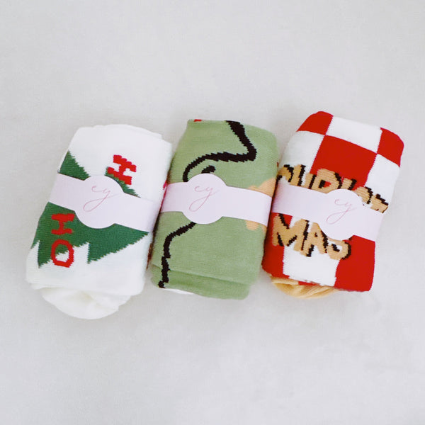 Set of three festive socks featuring holiday-themed designs, including Christmas colors and cheerful patterns, perfect for a cozy and jolly look.