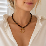Close-up of a woman wearing a brown beaded necklace with a gold clasp.