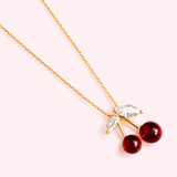 Necklace with cherry-shaped pendants on a light pink background