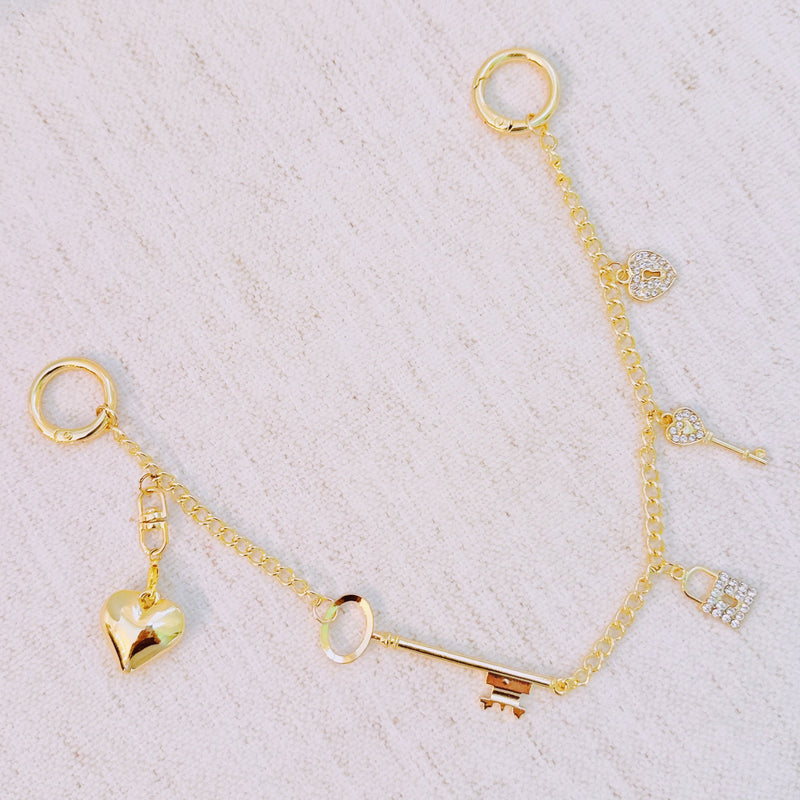 Gold bag charm with key, lock, and ring details – elegant purse accessory