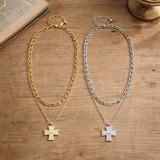 Two chain necklaces with cross pendants on a wooden surface.