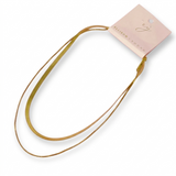 Gold hair tie with a pink packaging label on a white background