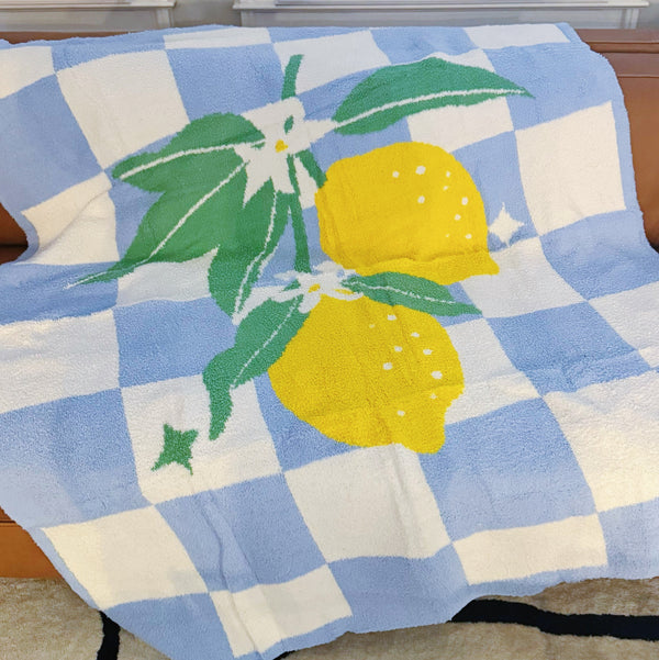 Soft blue and white checkered blanket featuring a charming leafy lemon design in vibrant yellow and green accents, perfect for adding a refreshing, cozy touch to any room.