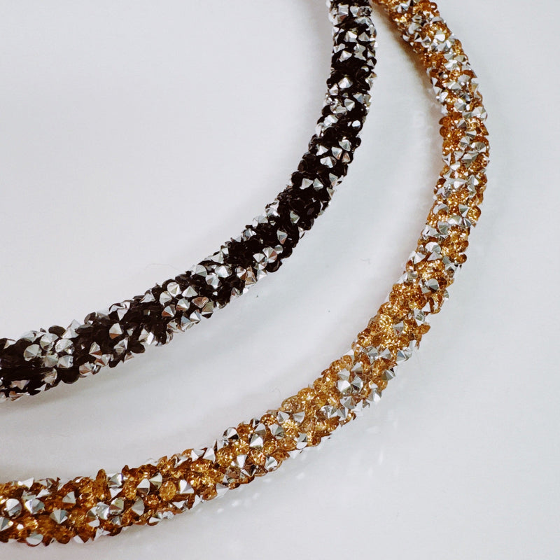 Set of two festive sparkle headbands in black and brown tones, each adorned with glittery “Let’s Celebrate” text and colorful accents, perfect for parties or special occasions.