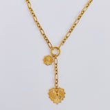 Gold-toned statement necklace featuring a bold chain and a cascading duo of engraved heart-shaped medallion pendants.