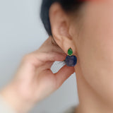 A pair of drop earrings featuring a uniquely sculpted irregular oval piece with a sparkle finish, topped by a small, contrasting accent element for added texture and elegance.