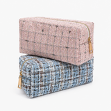 Two woven zip pouches stacked on a light gray background. The top pouch is dusty pink with black and white flecks, and the bottom pouch is light blue with black and white flecks.