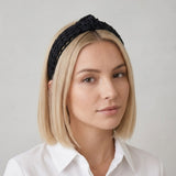 Woman wearing a black knitted headband against a plain background