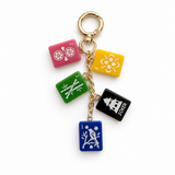 A gold-tone metal keychain featuring five colorful rectangular charms styled like Joker card suits: pink, yellow, green, black, and blue, each with white suit symbols, on a clean white background.