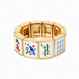 A gold-plated stretch bracelet designed to look like mahjong tiles, featuring white enamel faces with colorful Chinese tile designs including a blue bird, bamboo, and red characters.