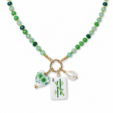 A beaded necklace featuring green and dark green round beads with gold spacer rings, a gold ring clasp, and three dangling charms: a white porcelain-style vase with green floral patterns, a white rectangular tile with green bamboo and the number 3, and a small white teardrop pearl.