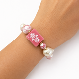 Pink bracelet with decorative beads on a wrist against a white background