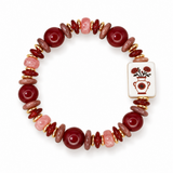 A beaded stretch bracelet featuring dark red polished beads, matte terracotta beads, pink stone beads, gold spacer rings, and a white rectangular tile charm with a red floral vase design, shown on a white background.