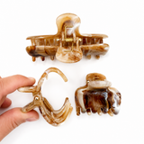 Set of three brown and clear hair clips on a white background