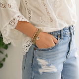 white lace top and jeans, beaded bracelets on a wrist, hand on the pocket