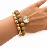 gold bead bracelet and natural taupe color bead bracelet with a coin crystal charm on wrist