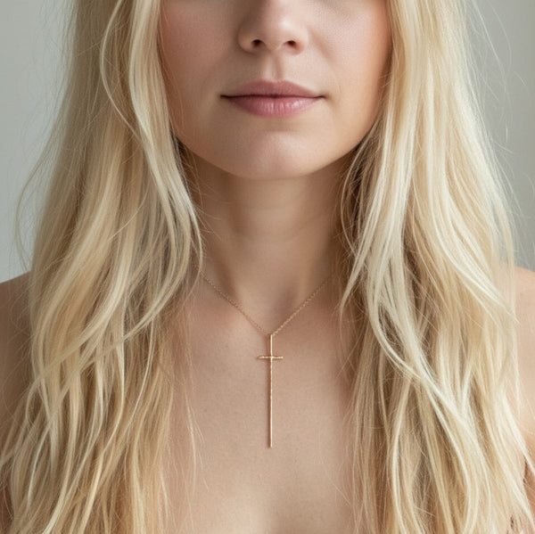 Delicate gold-tone necklace featuring a sleek vertical cross pendant on a fine chain, offering a modern and understated take on a classic faith-inspired design.
