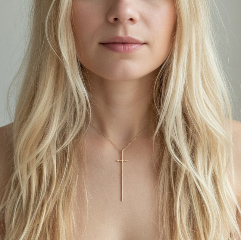 Delicate gold-tone necklace featuring a sleek vertical cross pendant on a fine chain, offering a modern and understated take on a classic faith-inspired design.