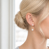 A pair of modern pearl earrings featuring a sleek gold-tone bar connecting two lustrous pearls—one smaller and one larger—for a minimalist yet elegant look. These dual pearl drop earrings combine classic sophistication with a modern silhouette.