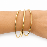 Gold hoop earrings on a person's ear against a white background