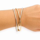 Gold bangle on a wrist against a white background