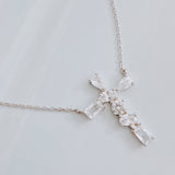 Silver cross pendant necklace featuring a mix of sparkling stone cuts in a modern design, suspended from a delicate chain.