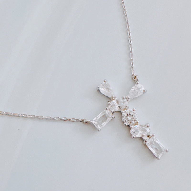 Silver cross pendant necklace featuring a mix of sparkling stone cuts in a modern design, suspended from a delicate chain.