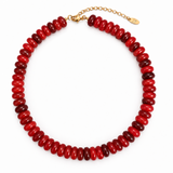 A chunky beaded necklace made of faceted hot red beads, completed with a gold-tone chain extender and clasp, shown on a plain white background.