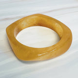 Chunky sculpted square bangle with a modern retro design, featuring a glossy finish and bold geometric shape.
