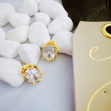 Chic stud earrings featuring a fluid, molten metal frame wrapped around a sparkling oval-cut crystal, offering a refined mix of organic shape and radiant shine.