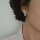 Chic stud earrings featuring a fluid, molten metal frame wrapped around a sparkling oval-cut crystal, offering a refined mix of organic shape and radiant shine.