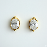 Gold earrings with clear gemstones on a light gray background