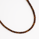 Single strand necklace featuring natural stone beads in warm, earthy tones with subtle color variations and organic shapes, offering a bohemian and grounded look perfect for everyday wear or layering.